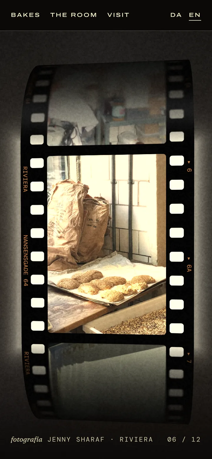 A strip of 35 mm film lit from behind in the dark: a flour sack and a tray of seeded buns by the window in the gate, the film curling away above and below.