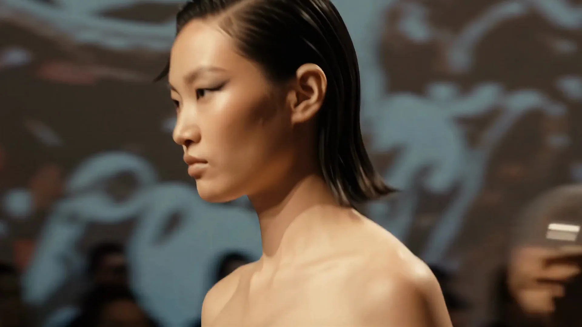 A model in profile on the runway, her hair slicked back